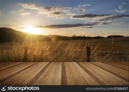 Beautiful Summer image of sun shining and backlighting countryside landcape with wooden planks floor