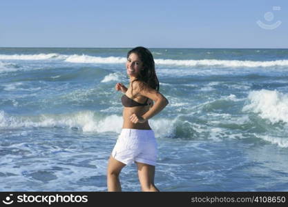 Beautiful summer indian brunette girl jumping on the blue beach