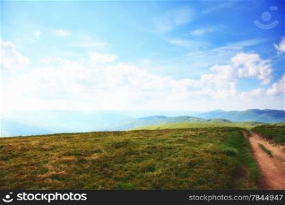 Beautiful summer landscape in the mountains. Pathway through the grassy hills, blue sky with clouds Bieszczady Poland