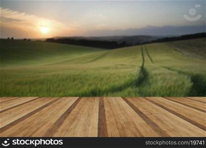 Beautiful Summer landscape of field of growing wheat crop during sunset with wooden planks floor
