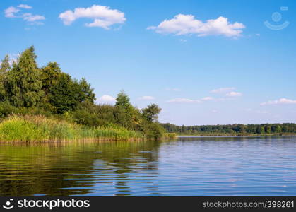 Beautiful summer landscape on the lake, the green grass and blue sky.