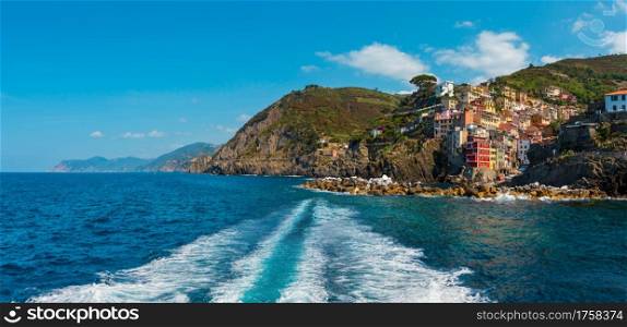Beautiful summer Manarola coast view from excursion ship. One of five famous villages of Cinque Terre National Park in Liguria, Italy, suspended between Ligurian sea and land on sheer cliffs.
