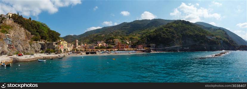 Beautiful summer Monterosso view from excursion ship. One of five famous villages of Cinque Terre National Park in Liguria, Italy. People unrecognizable. Three shots stitch high-resolution panorama.. Monterosso coast, Cinque Terre, Italy.