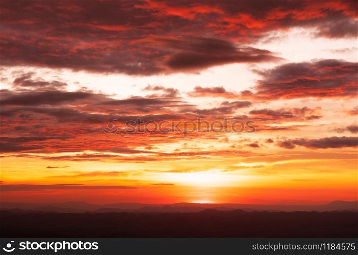 Beautiful summer red vibrant burning sunset or sunrise sky with clouds and mountain range