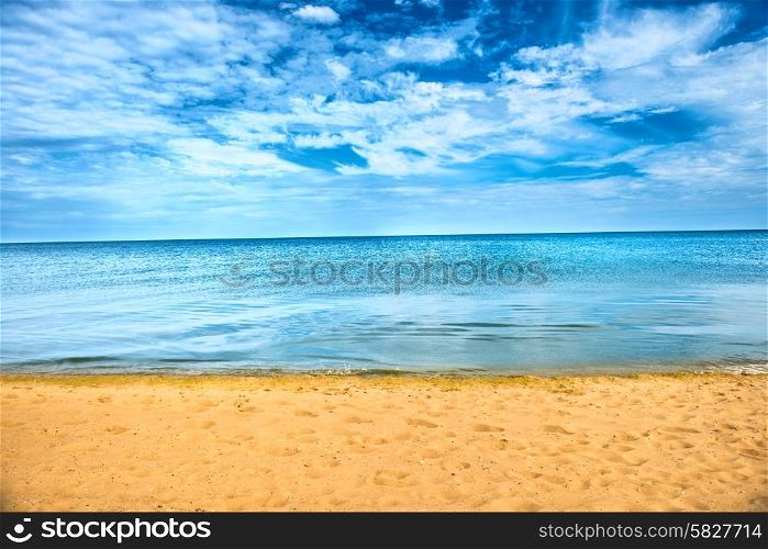 Beautiful summer sea abstract background. Golden sand beach with blue ocean and cloudscape and sunset