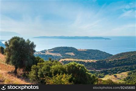 Beautiful summer seascape with a wooded coast, view from the Athos Peninsula, Sithonia and Amoliani island in mist in background (Halkidiki, Greece).