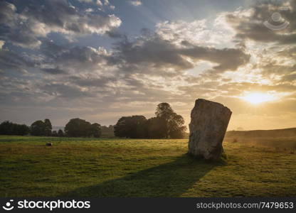 Beautiful Summer sunrise landscape of Neolithic standing stones in English countryside with gorgeous light with background mist