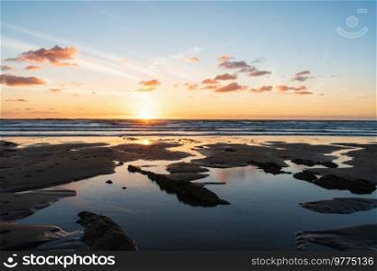 Beautiful Summer sunset landscape image of Widemouth Bay in Devon England with golden hour light on beach