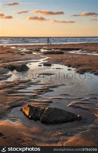 Beautiful Summer sunset landscape image of Widemouth Bay in Devon England with golden hour light on beach