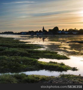 Beautiful Summer sunset landscape over low tide harbor with boats