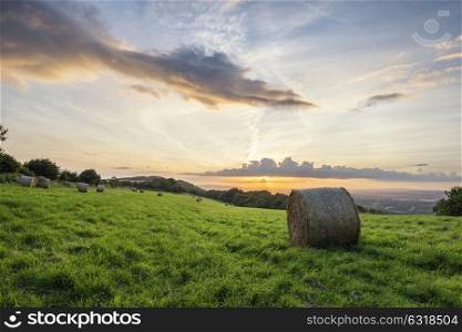 Beautiful Summer sunset over countryside landscape of field with hay bales