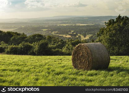 Beautiful Summer sunset over countryside landscape of field with hay bales