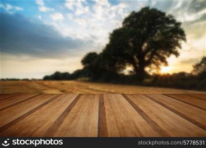 Beautiful Summer sunset over field of hay bales in countryside landscape with wooden planks floor