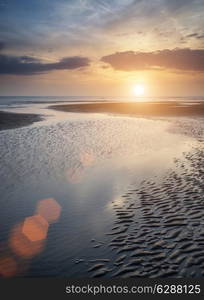 Beautiful Summer sunset over golden beach landscape with added lens flare effect