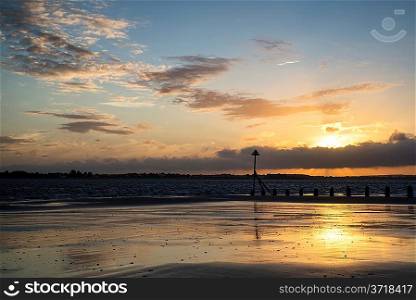 Beautiful Summer sunset sky reflected in wet low tide beach