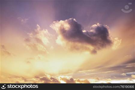 Beautiful Summer sunset sky with colorful vibrant clouds and sun beams across whole sky