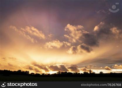 Beautiful Summer sunset sky with colorful vibrant clouds and sun beams across whole sky