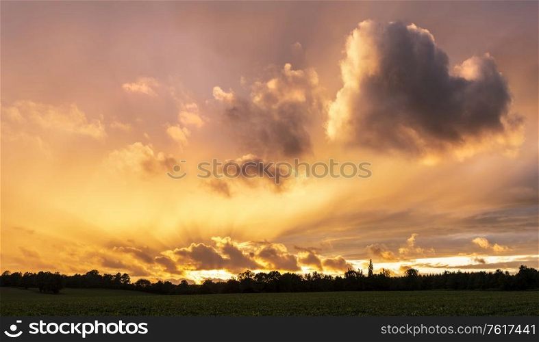 Beautiful Summer sunset sky with heart shaped cloud and colorful vibrant clouds and sun beams across whole sky