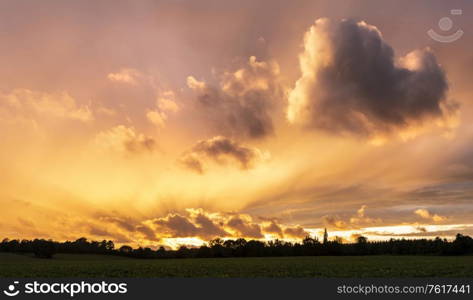 Beautiful Summer sunset sky with heart shaped cloud and colorful vibrant clouds and sun beams across whole sky