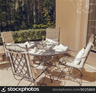 Beautiful summer terrace with garden furniture with white pillows surrounded by greenery on a warm, summer day