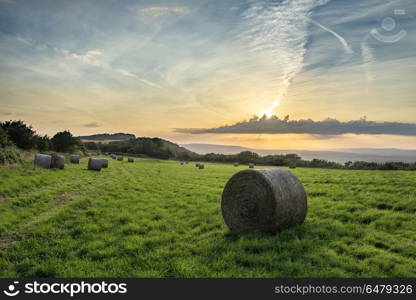 Beautiful Summer vibrant sunset over countryside landscape of fi. Beautiful Summer sunset over countryside landscape of field with hay bales