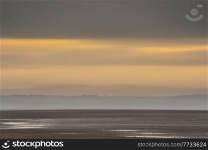 Beautiful sunrise landscape image of Talacre beach at surnise with dramatic sky and clouds 