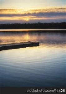 Beautiful sunrise landscape over lake with reflections and jetty