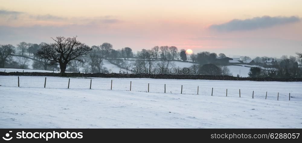 Beautiful sunrise landscape over snow covered Winter countryside