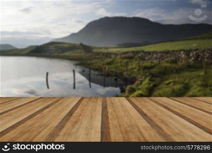 Beautiful sunrise mountain landscape reflected in calm lake. Beautiful sunrise reflected in calm Lakes landscape with wooden planks floor