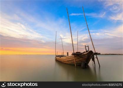 Beautiful sunrise over an old wooden fishing boat at sea