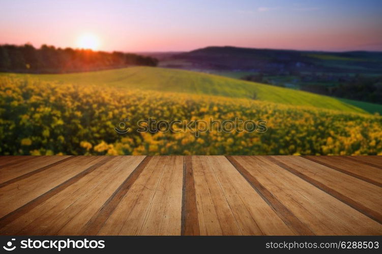 Beautiful sunrise over field of rapeseed in countryside in Spring with wooden planks floor platform. Beautiful sunrise over field of rapeseed in countryside in Spring with wooden planks floor