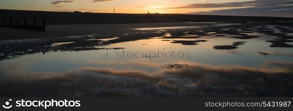 Beautiful sunrise panorama landscape reflected in pools on beach