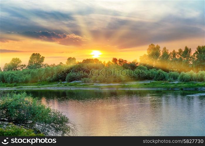 Beautiful sunset above a big river with green forest on the other coast and reflection on water