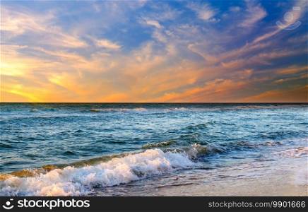 Beautiful sunset above sea or ocean. Vibrant and soft colors, magic light. Small clouds on the sky, reflection of sun in the water and sand on beach. Concept of romantic time on vacation in tropical.