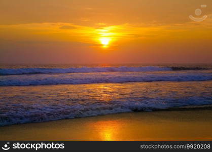 Beautiful sunset above sea or ocean. Vibrant and soft colors, magic light. Small clouds on the sky, reflection of sun in the water and sand on beach. Concept of romantic time on vacation in tropical.