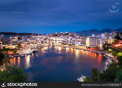 Beautiful sunset at Agios Nikolaos city, Port at Aegean sea. Crete,Greece. Peaceful harbor of Voulismeni Lake. Long promenade with restaurants. Panoramic view of seaport with yachts and boats at quay