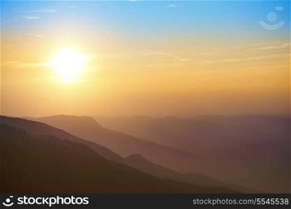 Beautiful sunset at the mountains. Colorful landscape with sun and blue sky