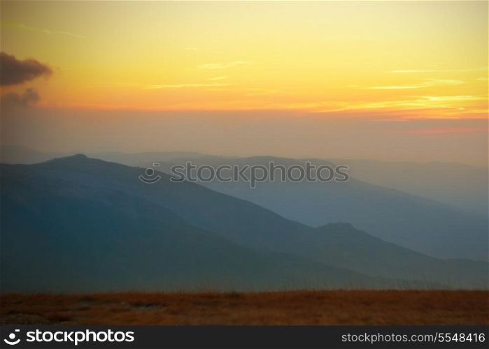 Beautiful sunset at the mountains. Colorful landscape with sun and blue sky