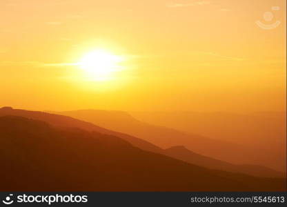 Beautiful sunset at the mountains. Colorful landscape with sun and orange sky
