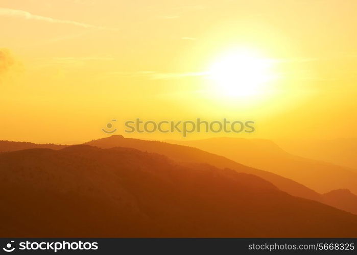 Beautiful sunset at the mountains. Colorful landscape with sun and orange sky