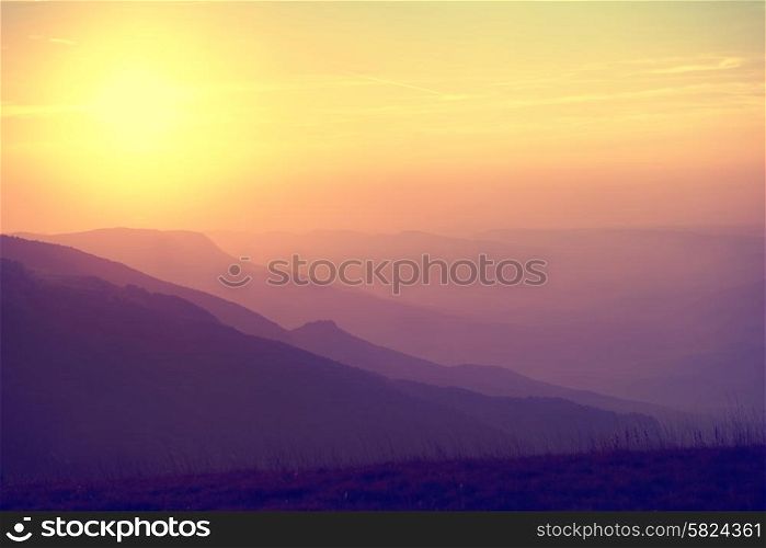 Beautiful sunset at the mountains. Colorful landscape with sun and orange sky. Colorized like instagram