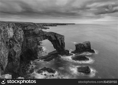 Beautiful sunset black and white landscape image of Green Bridge of Wales on Pembrokeshire Coast in Wales