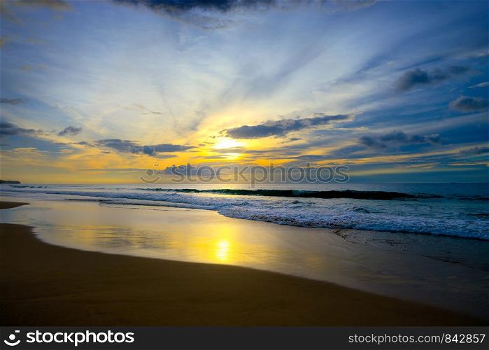 Beautiful sunset in ocean, sea waves and sand. Free space for text.