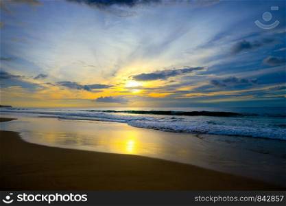 Beautiful sunset in ocean, sea waves and sand. Free space for text.