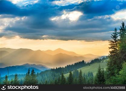 Beautiful sunset in the mountains. Landscape with sun shining through orange clouds