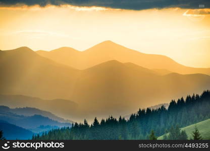 Beautiful sunset in the mountains. Landscape with sun shining through orange clouds