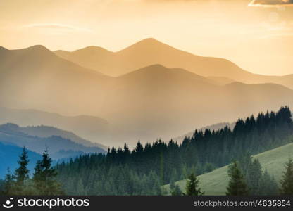 Beautiful sunset in the mountains. Landscape with sun shining through orange clouds