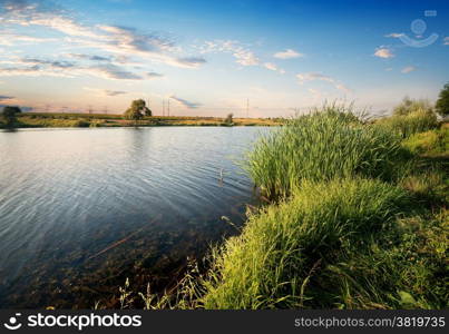 Beautiful sunset over calm river and green grass