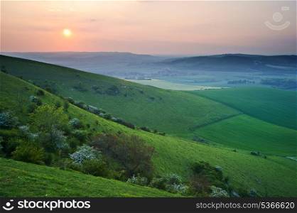 Beautiful sunset over English countryside landscape with light across hilltops