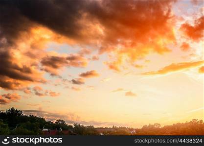 Beautiful sunset sky with clouds and sun light above green trees and village
